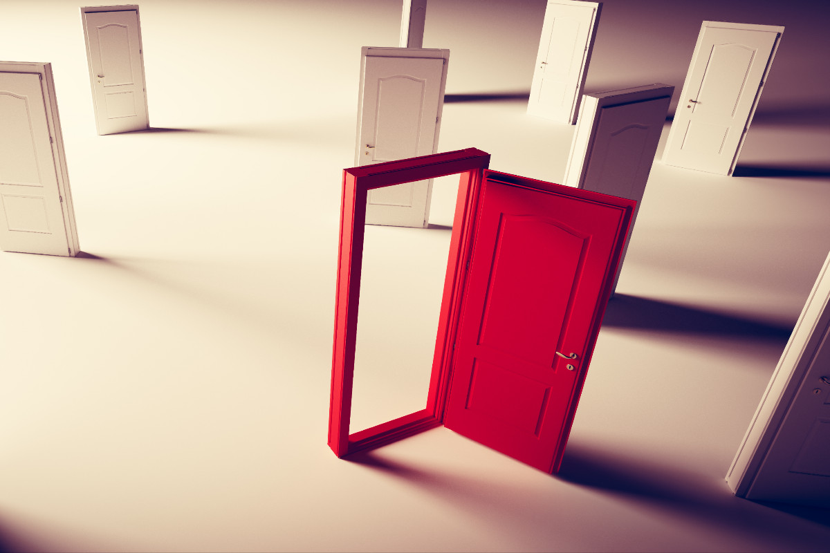 A series of closed white doors stand in a featureless room. One doorframe is painted in vibrant red, and this door stands open.