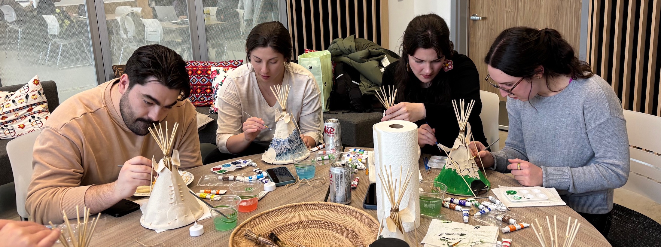 Four participants painting miniature tipis with sage having been smudged