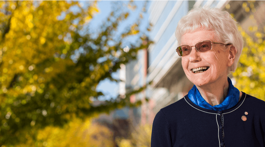 margaret-ann-armour A wide shot of Margaret-Ann Armour standing in front of yellow, autumnal trees in front of CCIS.