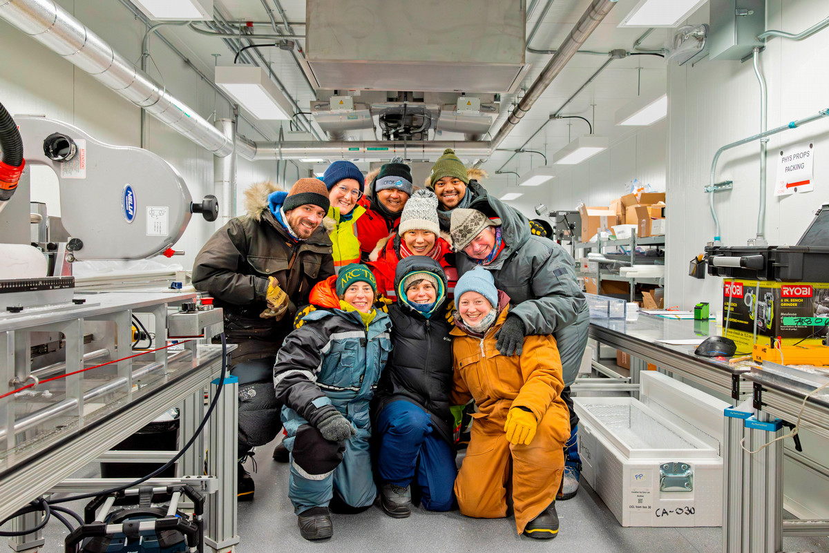 The Canadian Ice Core Lab team and visiting scholars huddle for a group photo in the lab, wearing PPE designed to withstand the freezing temperatures of the facility.